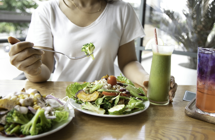 vrouw eet een gezonde ketogeen maaltijd met een groene smoothie