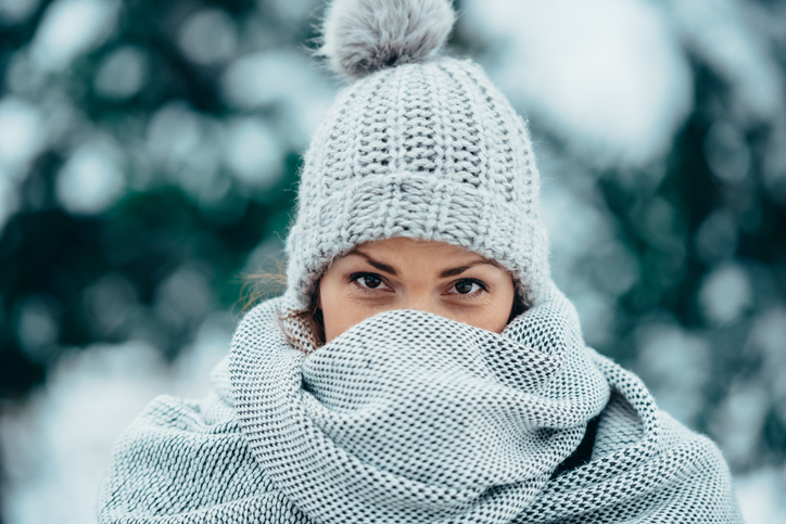 winterkwalen vrouw ingepakt met muts en sjaal in de winter tegen de kou