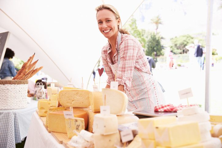 Lachende vrouw op een boerenmarkt met A2 melk kazen