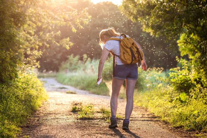 wandelende vrouw in de natuur met muggen en een insectenspray