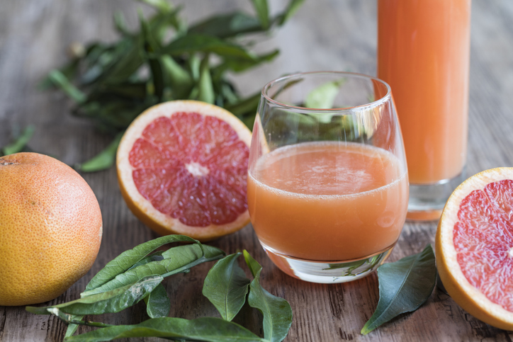 grapefruit en grapefruitsap met bladeren houten ondergrond