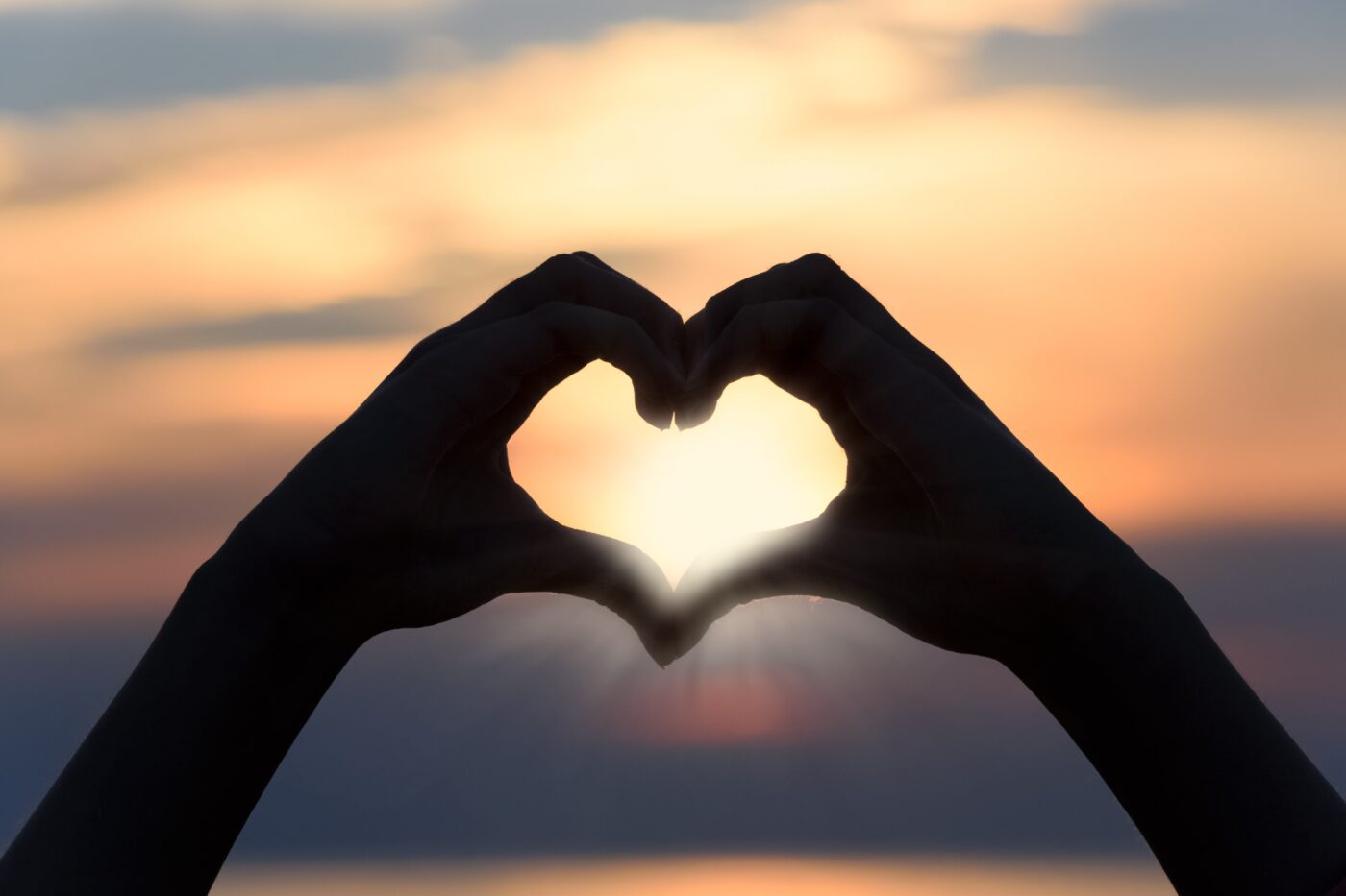 meditatiewandeling 1 2 handen die een hart vormen in de ondergaande zon